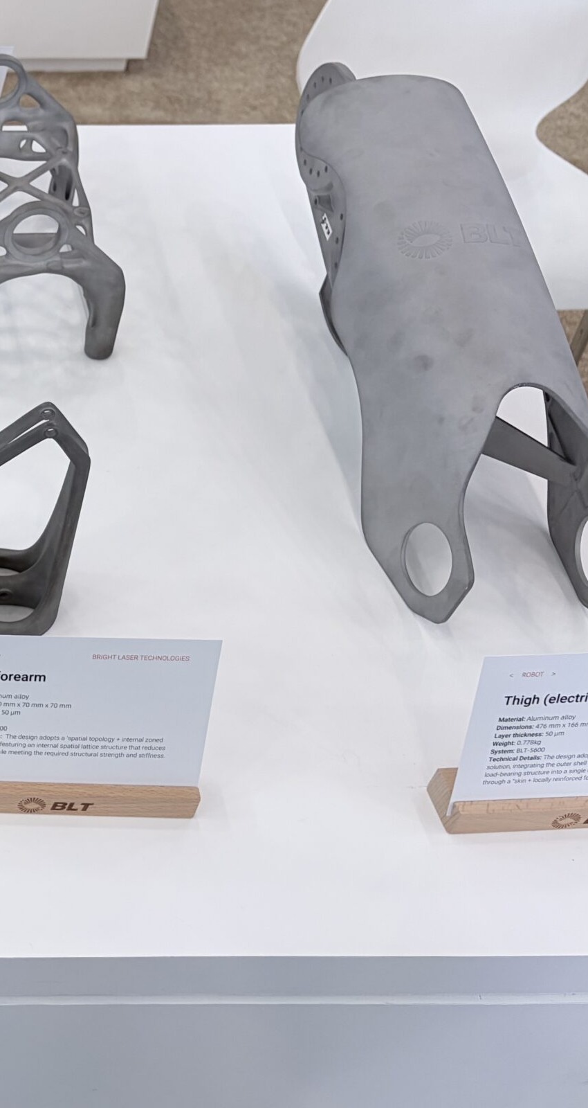 Metal additive robot thigh electric-drive shell blank on an exhibition table with placard