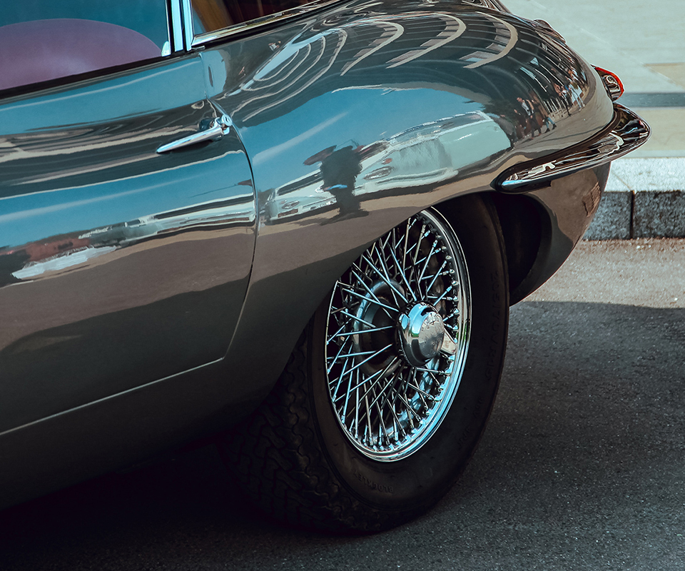 Rear three-quarter view of a classic coupe highlighting chrome wire-spoke wheel
