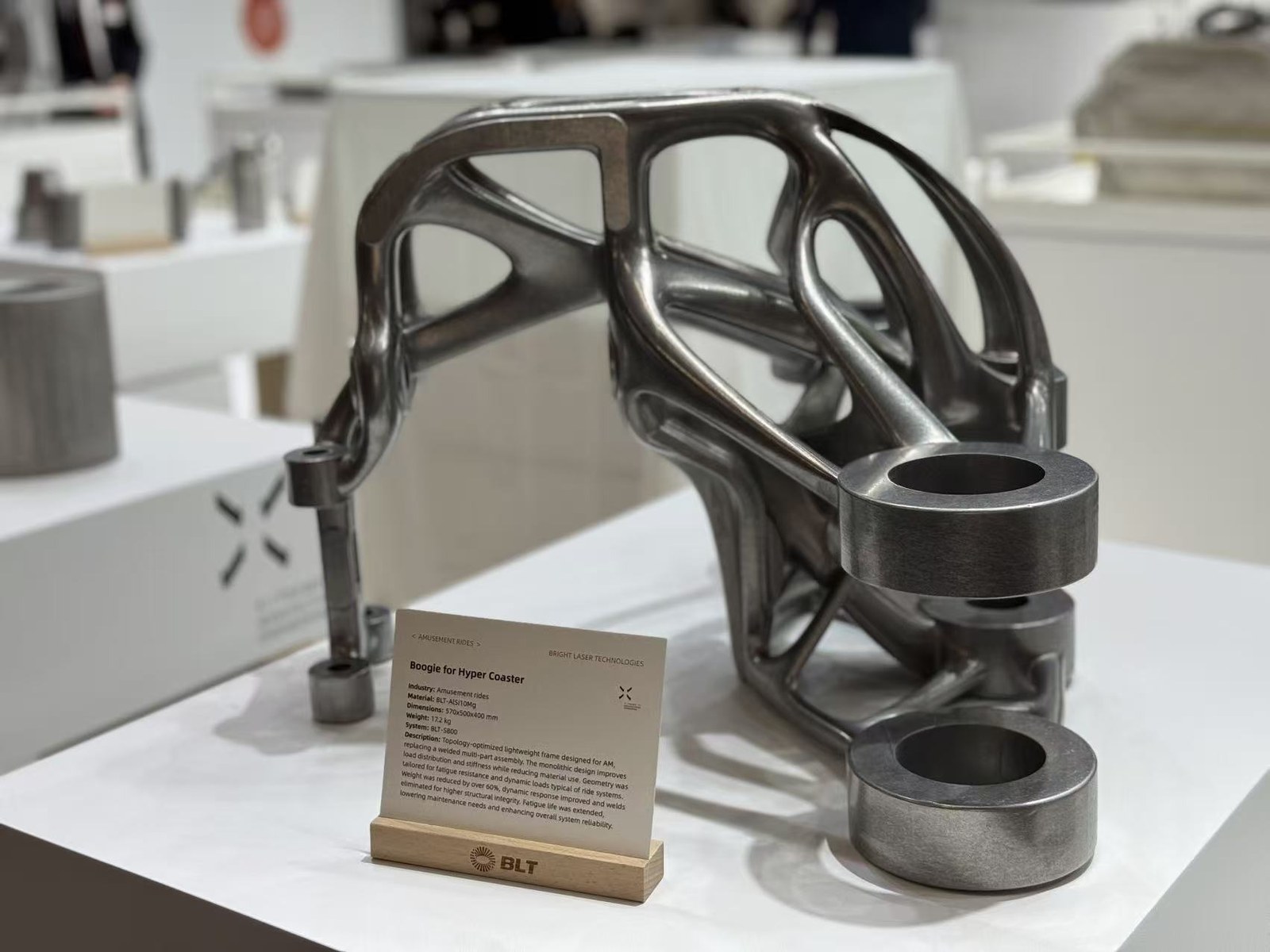 Topology-optimized metal additive cabin hinge blank on a white exhibit pedestal