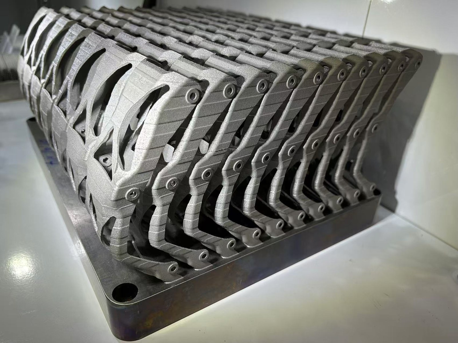 Nested metal additive wishbone bracket blanks remaining on a rectangular build plate